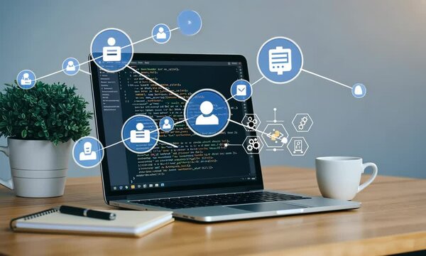 Laptop displaying code on desk with coffee cup and plant