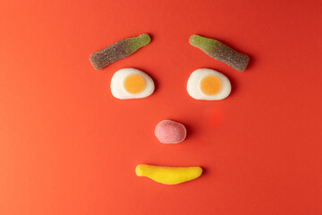 Funny face created with gummy candy on red background