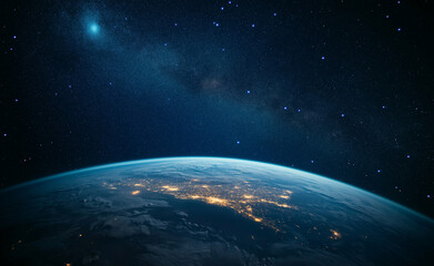 Fototapeta premium A close-up of Earth's surface with stars twinkling above. The background features dark blue and black hues, creating a striking contrast between the planet and the vastness of space.