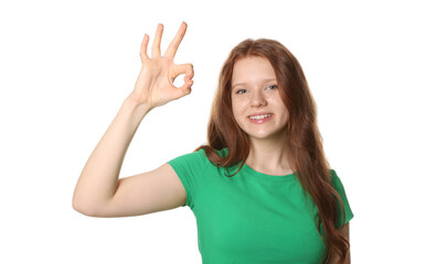 Fototapeta premium Beautiful teenage girl with freckles showing OK gesture on white background
