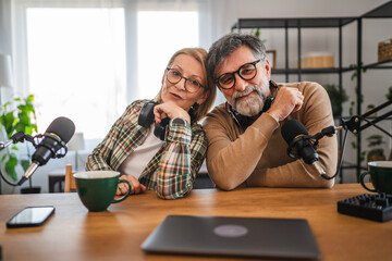portrait of man and woman host and guest record podcast at home studio