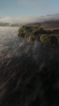 Drone video of mist on a lake in the morning sunlight