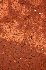 Close-up of cracked red earth in a desert-like landscape in Greece. The dry, parched ground forms intricate patterns, highlighting erosion and drought in this arid environment.