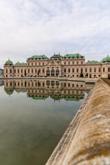 Belvedere Palace reflecting in pond during cloudy day in Vienna