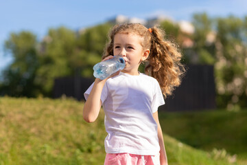 little girl drinking water from bottle in heat. kid suffering from thirst. prevention of...