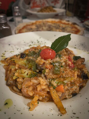 Mushroom risotto with a cherry and a bay leaf in a  white plate in Italian restaraunt
