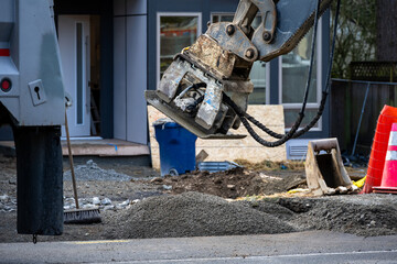 Roadworks covering trench dug for underground utilities with gravel and compacting with vibrating...