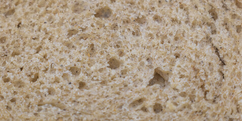 Close-up of the texture and pattern on a slice of freshly baked whole wheat sourdough bread. A macro photography shot focusing on the detailed textures of the bread's surface