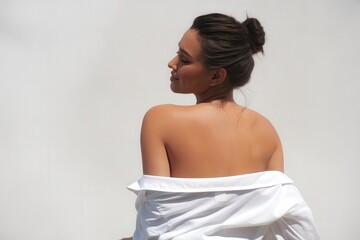 Back view of a confident woman with clean, glowing skin in minimalist fashion.
