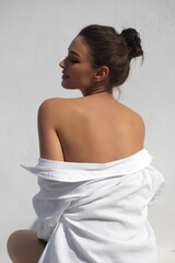 A woman in a white shirt poses gracefully, showcasing a relaxed and elegant style from a rear perspective.