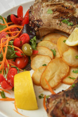 Pork chop with rib bone served with potato and green salad