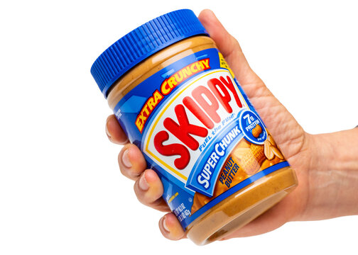 Woman hand holding a plastic jar of Skippy grand extra crunchy super chunk peanut butter isolated on a transparent background