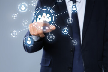 Targeting, recruitment, customer acquisition. Businessman touching virtual screen with scheme of human icons against grey background, closeup