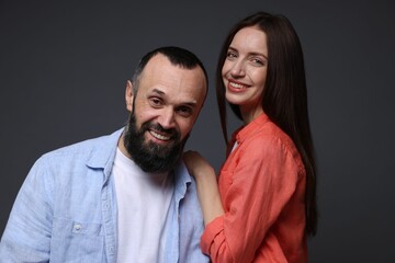 Fototapeta premium Portrait of happy daughter and father on dark grey background