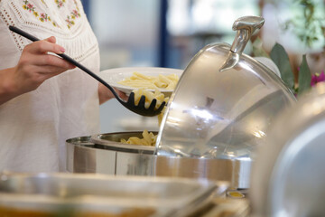 Woman taking food from a buffet line	