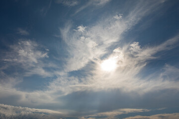 Bright morning sun shining through wispy white clouds in the sky