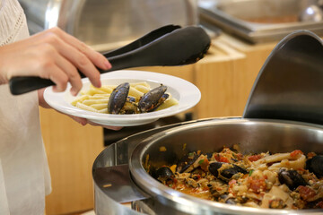 Woman taking food from a buffet line	