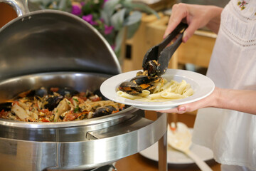 Woman taking food from a buffet line	