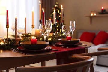 Festive table setting in room decorated for Christmas, closeup. Bokeh effect