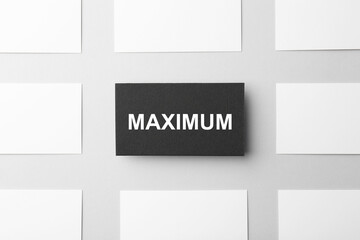 Obraz premium Black business card with word Maximum among empty white ones on light background, flat lay
