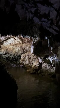 The bright and colorful Abrskil cave. A gallery-type cave in the mountains of Abkhazia with many stalactites and stalagmites, colorful lighting. Otapskaya (Otap cave). 4K