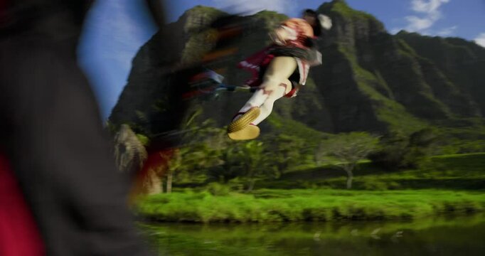 Low, steady cam shot of fantasy woman sliding backwards on wires as ninja attacks her