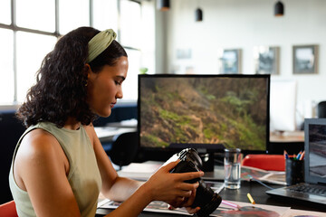 Woman reviewing camera in modern office, focusing on photography work, copy space