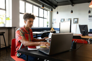 Young man working on laptop in modern office, focusing on project tasks