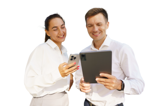 Couple smiling while using smartphone and tablet outdoors during daytime at a bright location