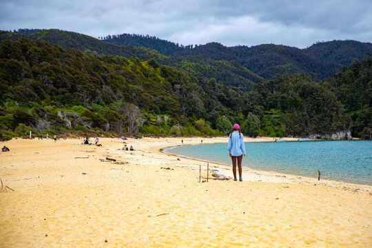 hiker girl enjoys a walk on the famous beach in Anchorage Bay in Abel Tasman National Park, New Zealand South Island - Powered by Adobe