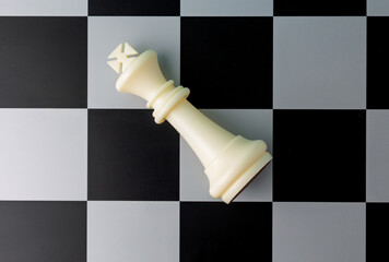 White king lying down defeated on chessboard: signifying checkmate and game over