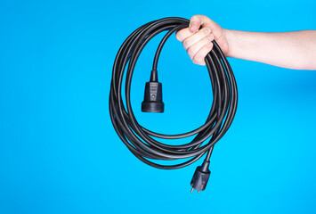 Person holding utility cable with socket and plug.
