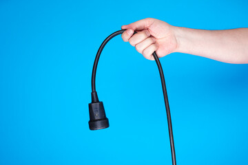 Close-up of a person holding durable utility cable with plug and socket, concept of electricity and energy supply.
