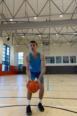 Obraz premium Young man in gym holding basketball, preparing to make shot