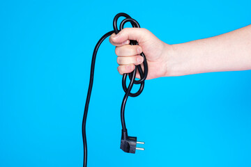 Coiled extension cord with plug in human hand.
