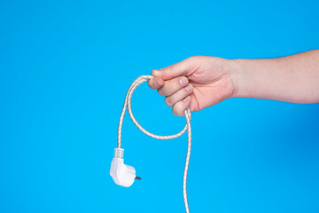 Hand with coiled cable on blue background.