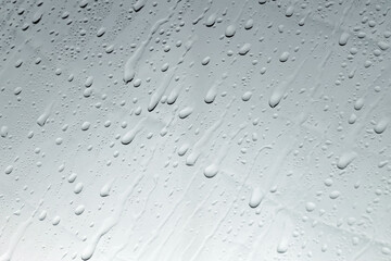 Water drops on grey glass surface, closeup