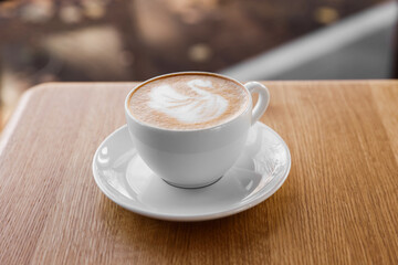 Cup of aromatic coffee on wooden table in cafe, closeup