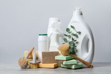Eco-friendly cleaning products, supplies and eucalyptus branches on wooden table