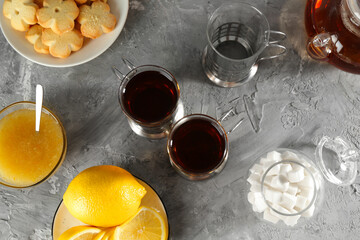 Glasses of tea in metal holders served on grey textured table, flat lay