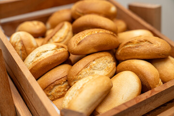 Freshly baked bread rolls in a wooden basket, perfect for breakfast or bakery product marketing, delicious golden crust and soft texture. Mini bread baguettes in basket. pieces to accompany food