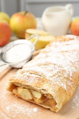 Delicious strudel with apples and powdered sugar on table, closeup