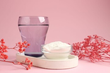 Collagen powder in bowl, glass of water and gypsophila branches on pink background, closeup