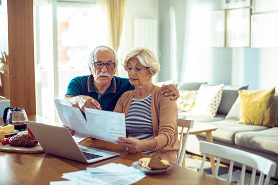 Senior couple managing finances and bills at home with laptop