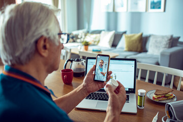 Senior man having video call with doctor from home