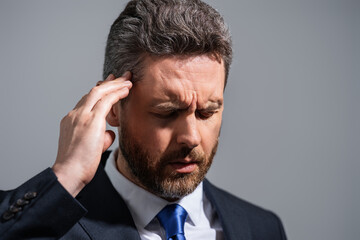 Tired man having a terrible headache. Exhausted man feeling unhealthy, upset about headache illness. Stressed middle-aged man with headache isolated on gray. Migraine and headache concept.