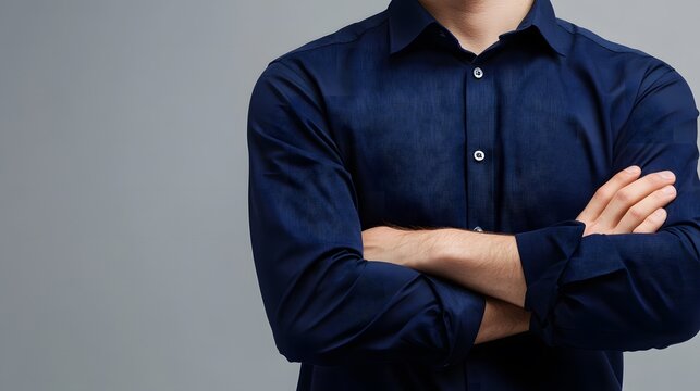 Confident businessman in blue shirt, arms crossed, exuding professionalism and authority