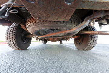  1990 covered pickup truck, lifted American 4X4 SUV off-road vehicle underneath close up details, frame, axle, suspension, differential, exhaust etc.
