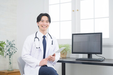 背景に緑がある医者、精神科医など若いドクターのイメージ　転職や求人などにも　カメラ目線
