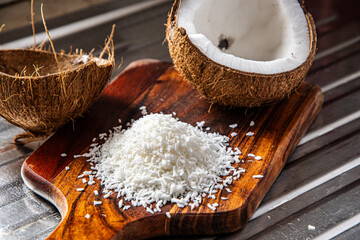 A split coconut lies on a wooden kitchen board, its fresh flesh sparkling in the light, and a coconut mug stands nearby as if inviting you to enjoy the tropical mood.